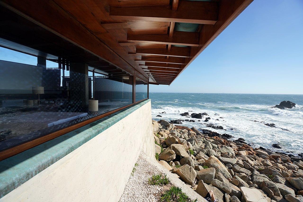 Concrete and timber structure built over coastal rock, opening views to the Atlantic ocean. Architecture integrated with the landscape.