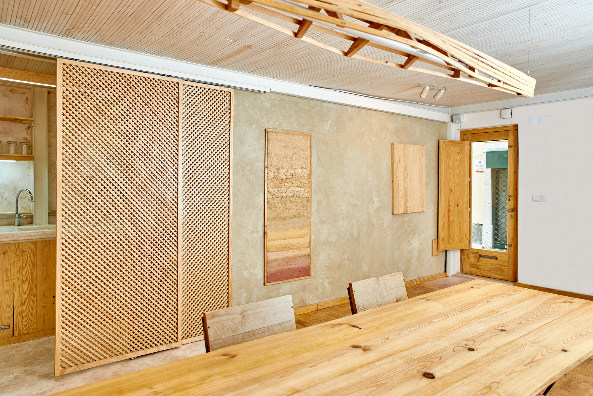 Interior of a contemporary project in Lisbon with rammed earth wall and wooden details.