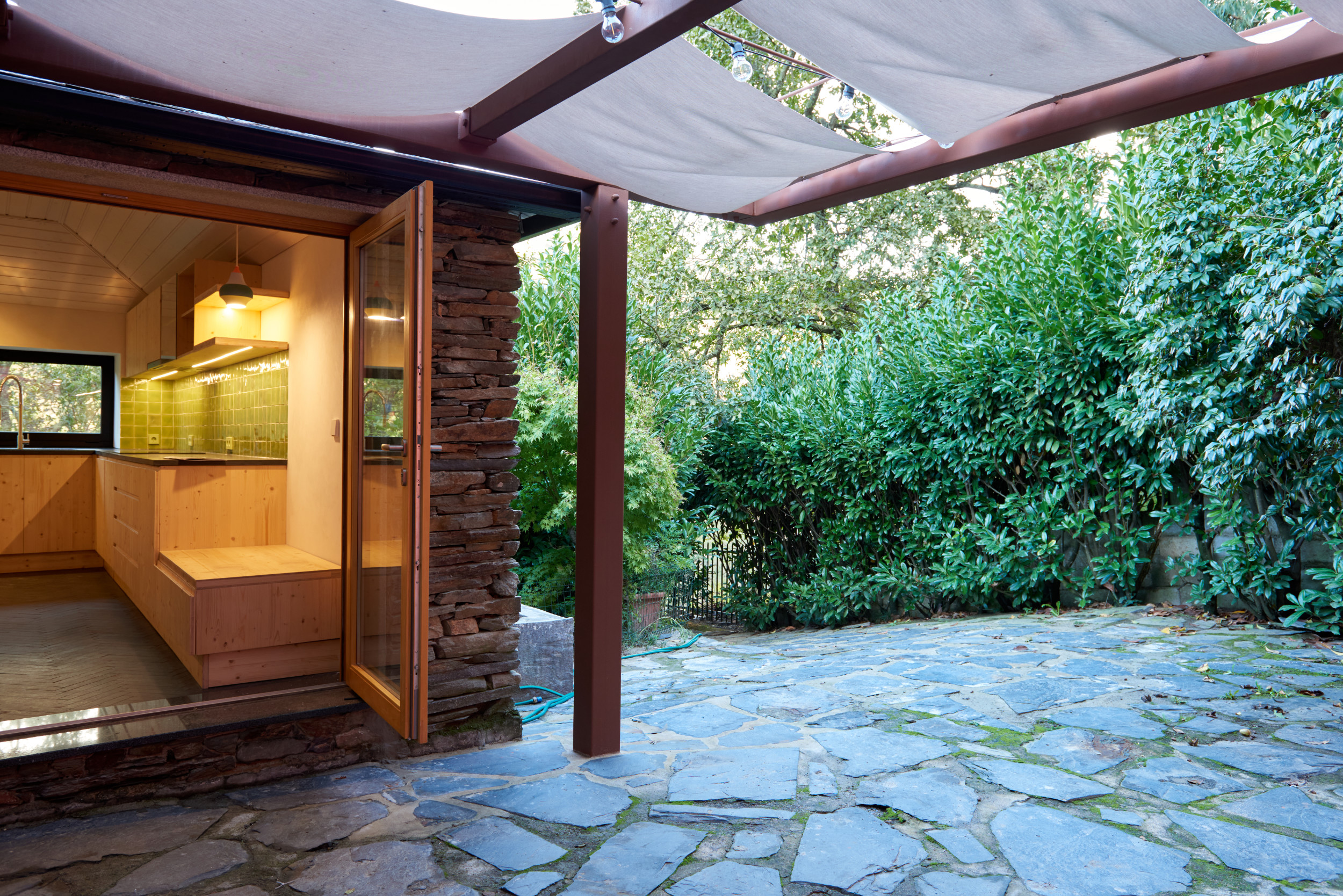 Schist house renovation with biobased materials, shading system, and cross ventilation courtyard