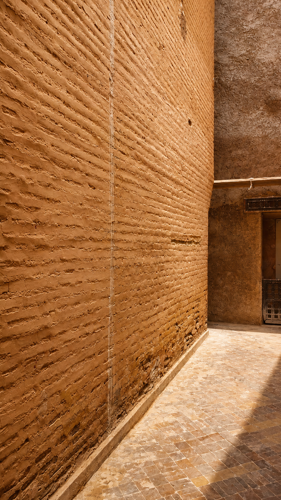 Earthen wall at the Saadian Tombs in Marrakech, Morocco, showing traditional rammed earth construction, texture and natural light.
